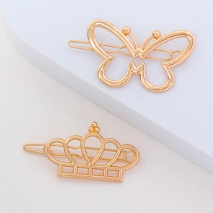 Lot de barrettes à cheveux dorées en métal papillon et couronne sur fond blanc épuré