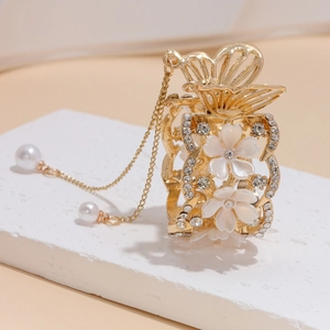 Dettaglio molletta per capelli a farfalla dorata con fiori bianchi, strass e nappe di perle