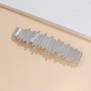 Vue détaillée de la pince à cheveux géométrique argentée avec texture métallique plissée chic