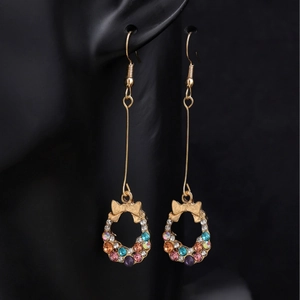 Long gold bow earrings with colorful rhinestones on a black background model