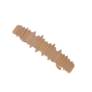 Détail de la pince à cheveux en métal or rose avec rainures verticales et bords ondulés