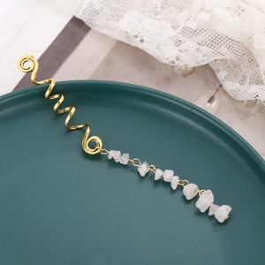Detail of golden spiral dreadlock accessory with raw white natural stone pendants