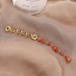 Détail de l'accessoire de cheveux en spirale dorée avec pierres naturelles orange