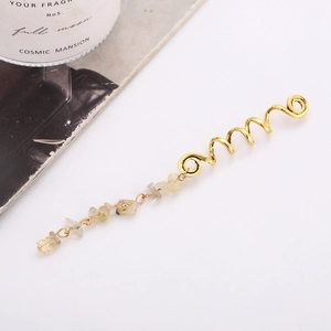 Détail d'un bijou de cheveux spirale doré avec pendentif en pierre naturelle jaune translucide