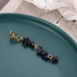 Golden spiral dreadlock hair clip with blue sandstone crystal charms on a green plate