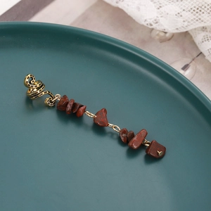 Macro detail of alloy spring braid accessory with red natural stone charms on a plate