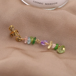 Détail macro du clip d'oreille spirale doré avec des pendentifs en pierres naturelles