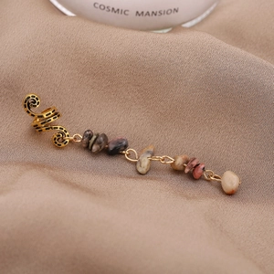 Gros plan d'un ear cuff vintage doré avec pampilles en pierres naturelles