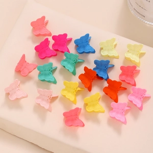 Dettaglio di mini mollette a farfalla colorate con finitura opaca e molla metallica