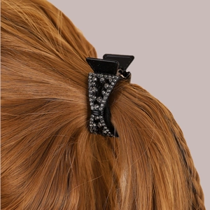 Small black bow hair claw clip with grey rhinestones on long brown hair back view