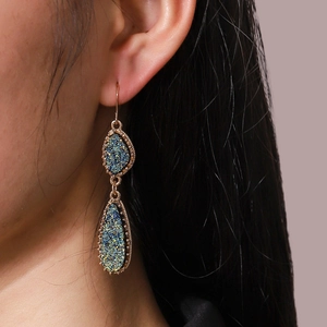 Boucles d'oreilles double goutte dorées avec cristal de résine bleu-vert sur mannequin