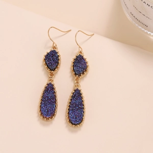 Détail des boucles d'oreilles en cristal violet et bleu avec cadre goutte doré