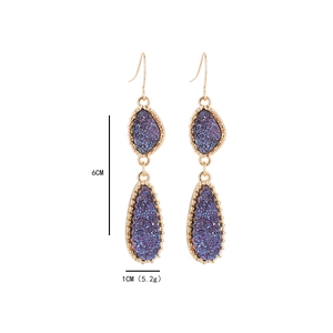Détail montrant la longueur de 6 cm et la largeur de 1 cm des boucles d'oreilles cristal