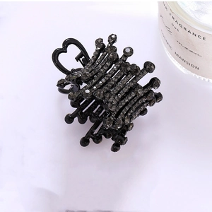 Close-up of black high ponytail claw clip featuring grey rhinestones and heart-shaped handle