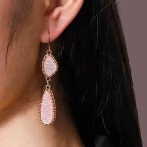 Gros plan détaillé des boucles d'oreilles doubles gouttes rose druzy avec bord doré