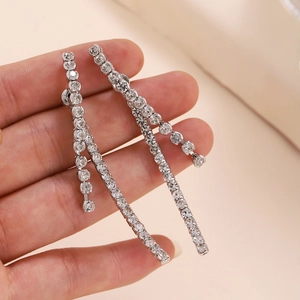Longues boucles d'oreilles à pampilles en strass étincelants tenues dans la main