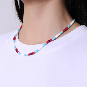 Close-up of a colorful beaded necklace with blue and red glass beads on a model's neck