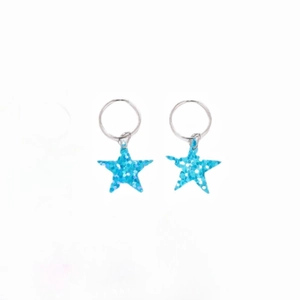 Close-up of Y2K blue glitter star charms on silver metal hair rings for dreadlock styling