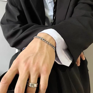Detail of silver Cuban link chain bracelet and minimal wide ring on hand