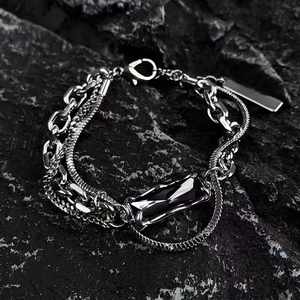 Detail of multi-layered silver steel bracelet with black stone on dark rock background