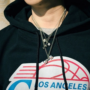 Gros plan des pendentifs haltères argentés avec gravure 5KG sur un collier à chaîne fine