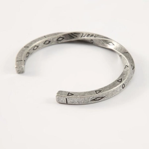 Detailed macro shot of vintage Mobius steel cuff bracelet with geometric totem engravings