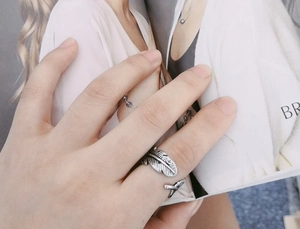 Close-up of retro silver feather ring with detailed texture on hand against magazine