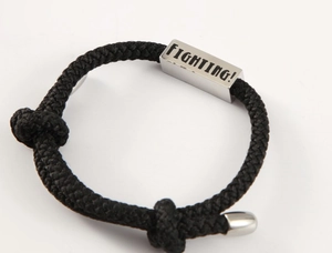 Detailaufnahme vom schwarzen geflochtenen Armband mit gravierter Fighting Silberplatte