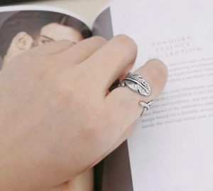 Detailed view of vintage silver feather ring with intricate engraved textures on a hand