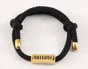 Nahaufnahme eines handgewebten schwarzen Kordelarmbands mit goldener Titanstahlecke