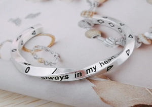 Macro shot of silver Viking Möbius cuff with 'Always in my heart' engraved detail