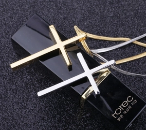 Macro detail of polished gold and silver cross pendants on minimalist snake chains