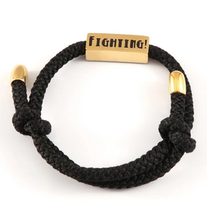 Geflochtenes Seilarmband mit Goldblock und graviertem Fighting-Text auf weißem Hintergrund
