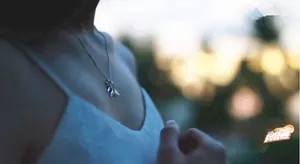Detail of a silver fish tail pendant necklace worn by a woman, showing elegant clavicle style