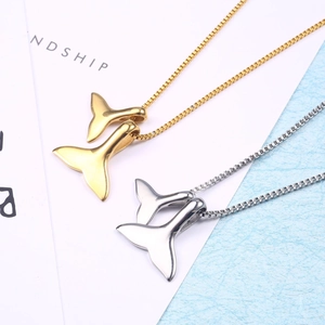 Close-up of gold and silver whale tail pendant necklaces with mirror finish on box chains