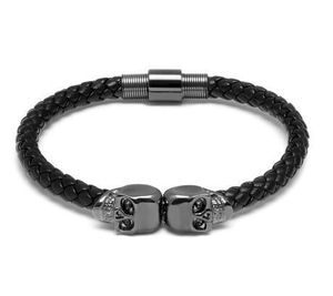 Detail of black braided leather bracelet with dark grey metal skull charms and magnetic clasp