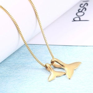 Close-up of golden double whale tail pendants on a sleek box chain necklace