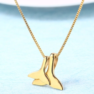 Detailed close-up of a gold fishtail pendant necklace with a polished mirror finish