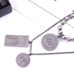 Detail of vintage layered beaded chain with engraved silver coin and rectangle pendants