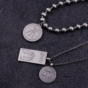 Macro shot of vintage silver necklaces with engraved metal pendants and ball chain texture