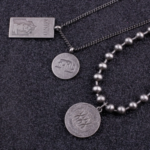 Macro detail of retro silver stacked necklaces with FLY and portrait pendants