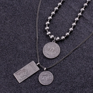Detail of layered titanium steel necklaces with engraved round charms and rectangular tags