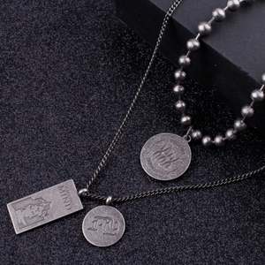 Detail of layered titanium necklaces with engraved round pendants and vintage dog tags