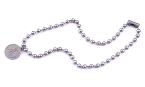 Detail view of the silver bead chain necklace with vintage logo coin pendant