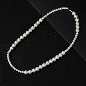 Gros plan sur un collier de perles blanches minimaliste avec fermoir métallique argenté