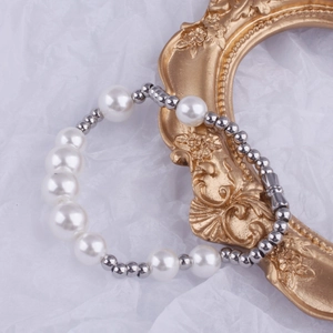 Detail of elegant beaded bracelet with alternating pearls and silver beads on white fabric
