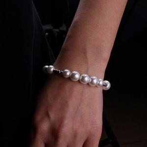 Elegant pearl bracelet with metallic accent beads on wrist over dark background