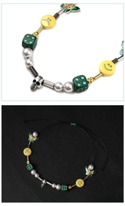 Close-up of hip hop necklace with yellow smiley, skull, dice and butterfly charms