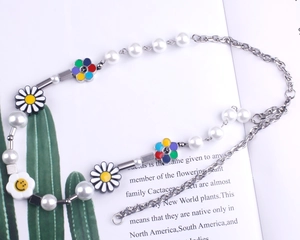 Détail de pendentifs marguerites colorés et de fleurs souriantes sur collier de perles