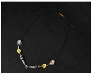 Detail of beaded hip hop necklace with yellow smiley, dice, and silver skull charms